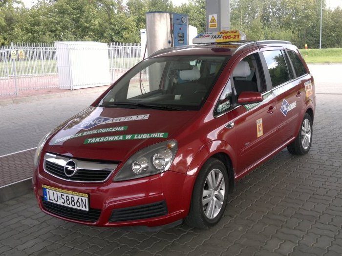 Bordowa taksówka Opel Zafira na CNG z napisem Pierwsza ekologiczna taksówka w Lublinie przy stacji tankowania