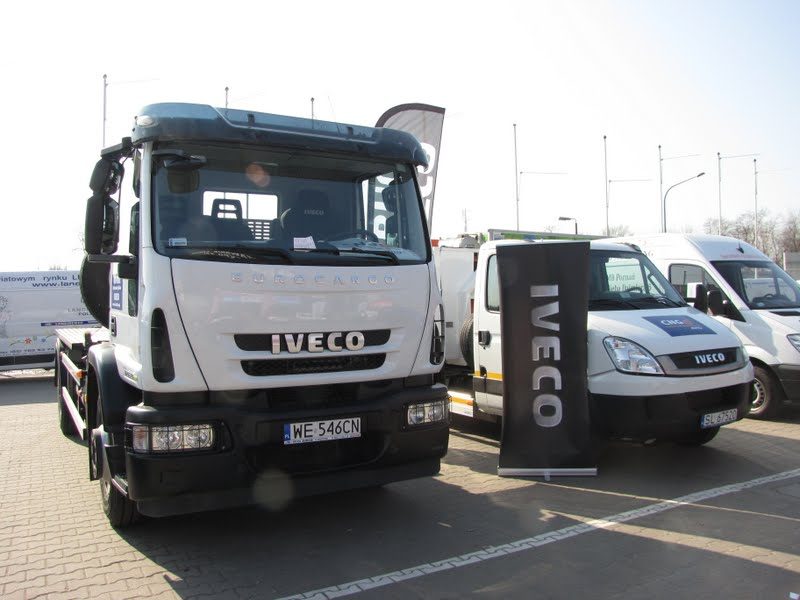 Ciężarówka Iveco EuroCargo na CNG obok dostawczaka Iveco Daily z banerem marki na parkingu wystawowym