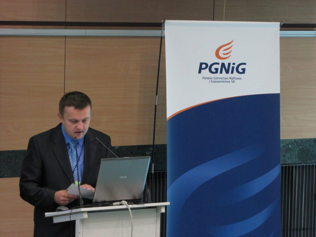 Mężczyzna w garniturze wygłaszający wykład podczas konferencji CNG
