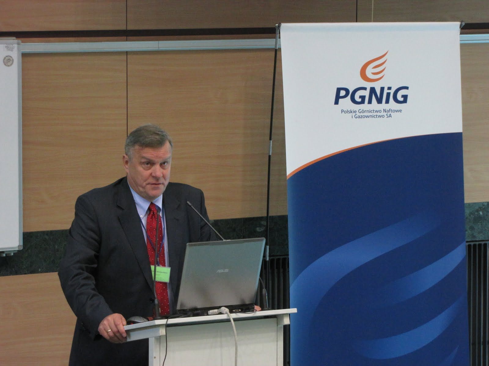 Wyższy oficer w garniturze i czerwonym krawacie na mównicy konferencji