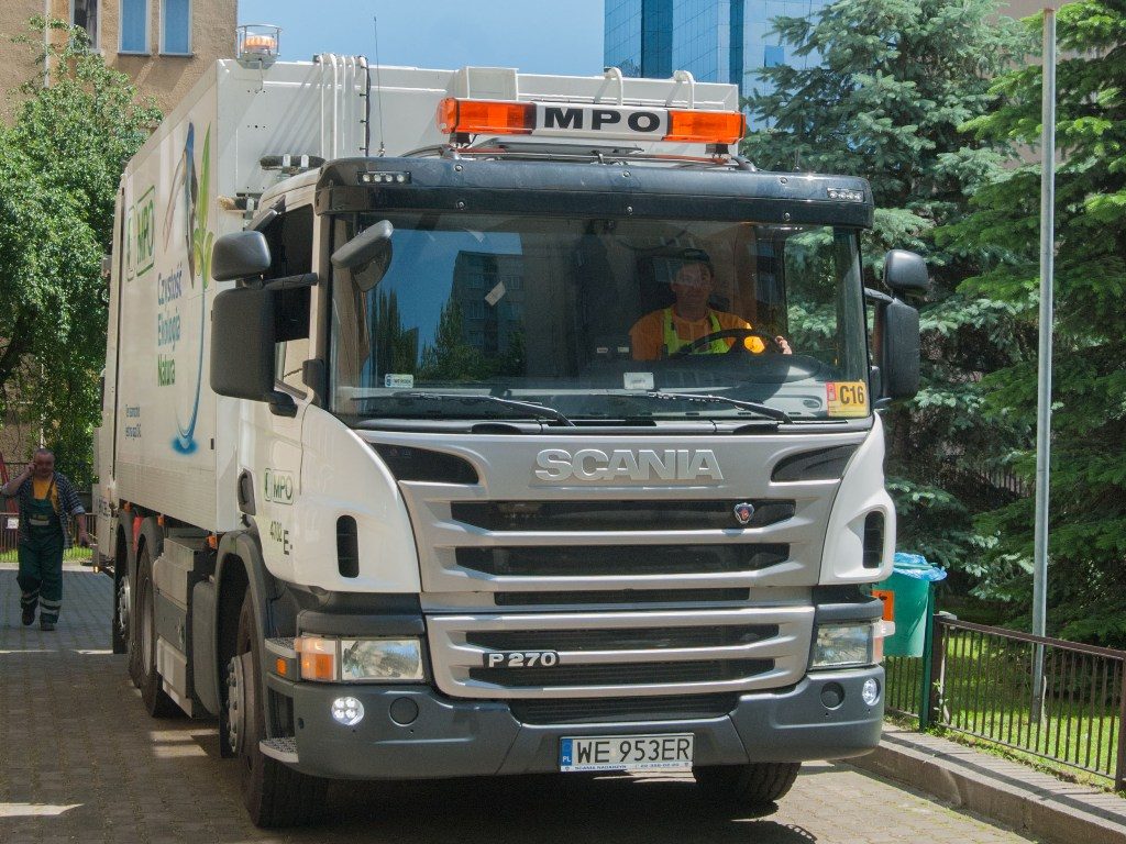 Scania P270 CNG na ulicy Warszawy z kierowcą za kierownicą i zielonym logo MPO na boku